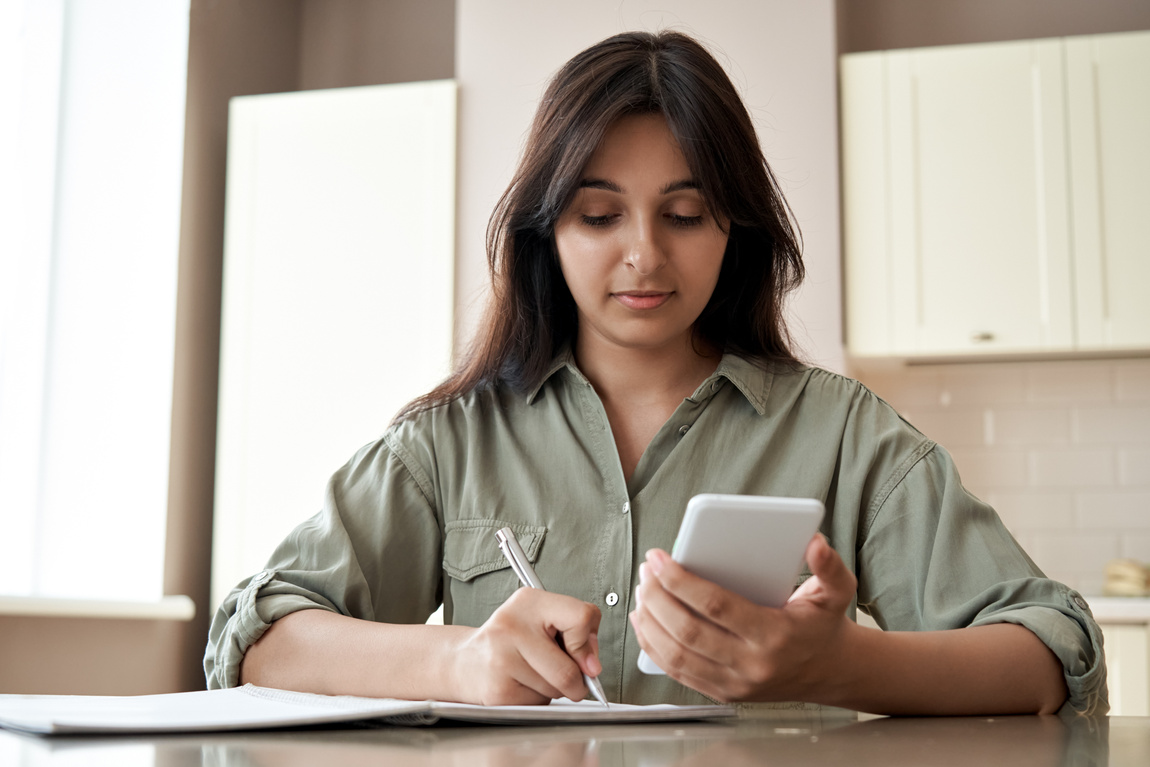 Indian Girl Holding Phone Write Notes at Home 